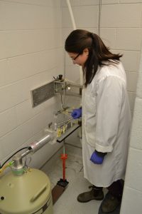 A researcher stands next to equipment. 