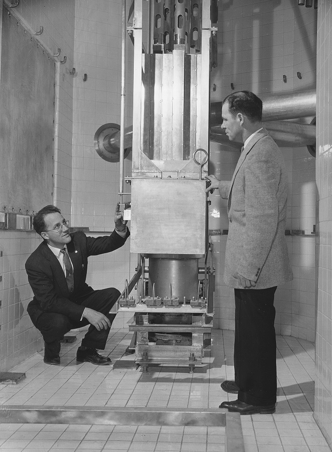 Two researchers stand next to MNR's control rods on the reactor pool floor in 1959.