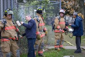 Two men use handheld radiation detectors to check for contamination on firefighters.