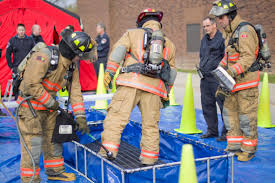 Three firefighters stand on a blue tarp and are checked for radiation contamination.