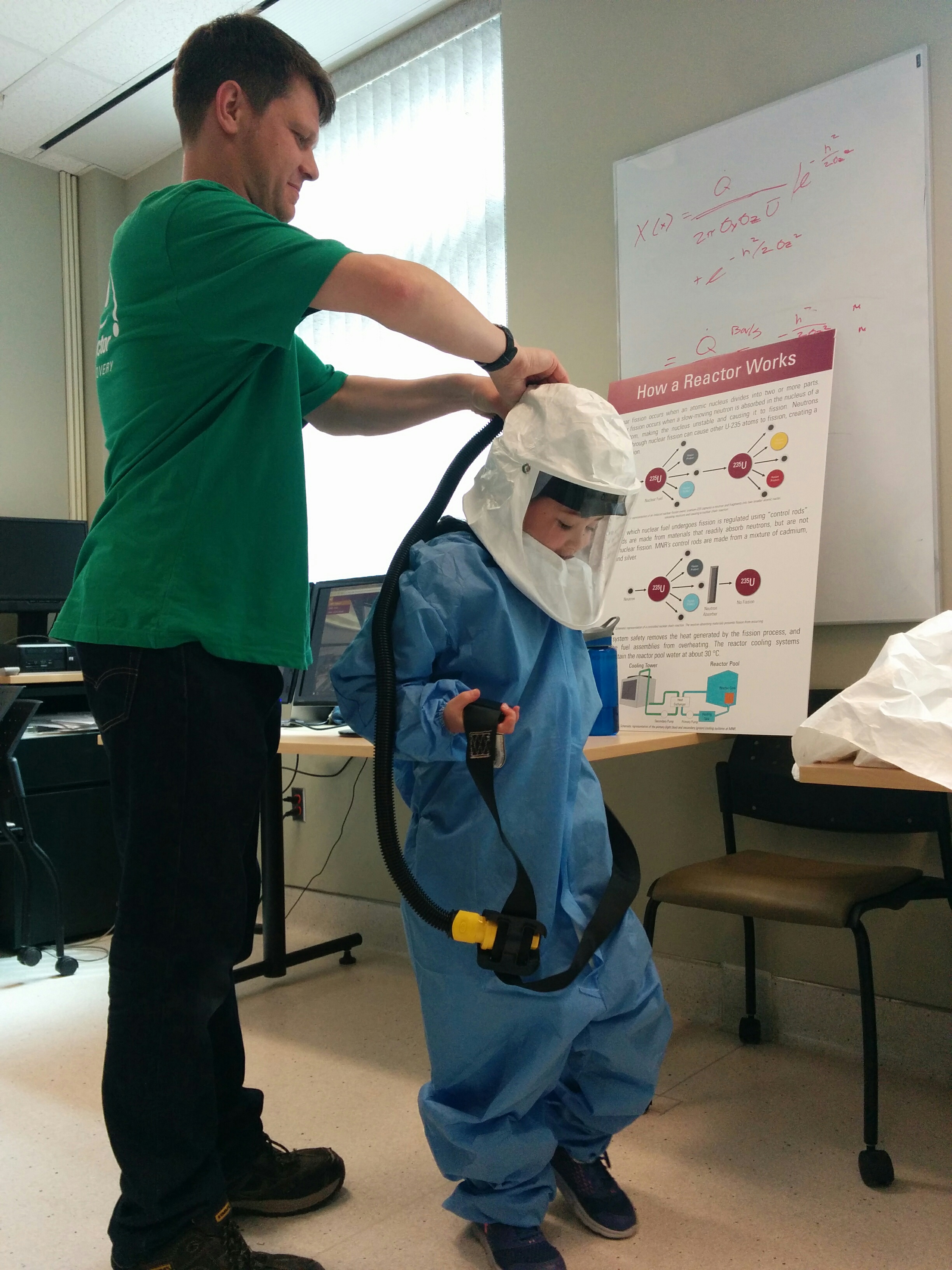 A McMaster staff member helps a visitor put on PPE.