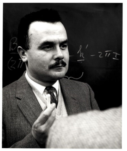 Headshot of Bertram Brockhouse standing in front of a chalkboard.