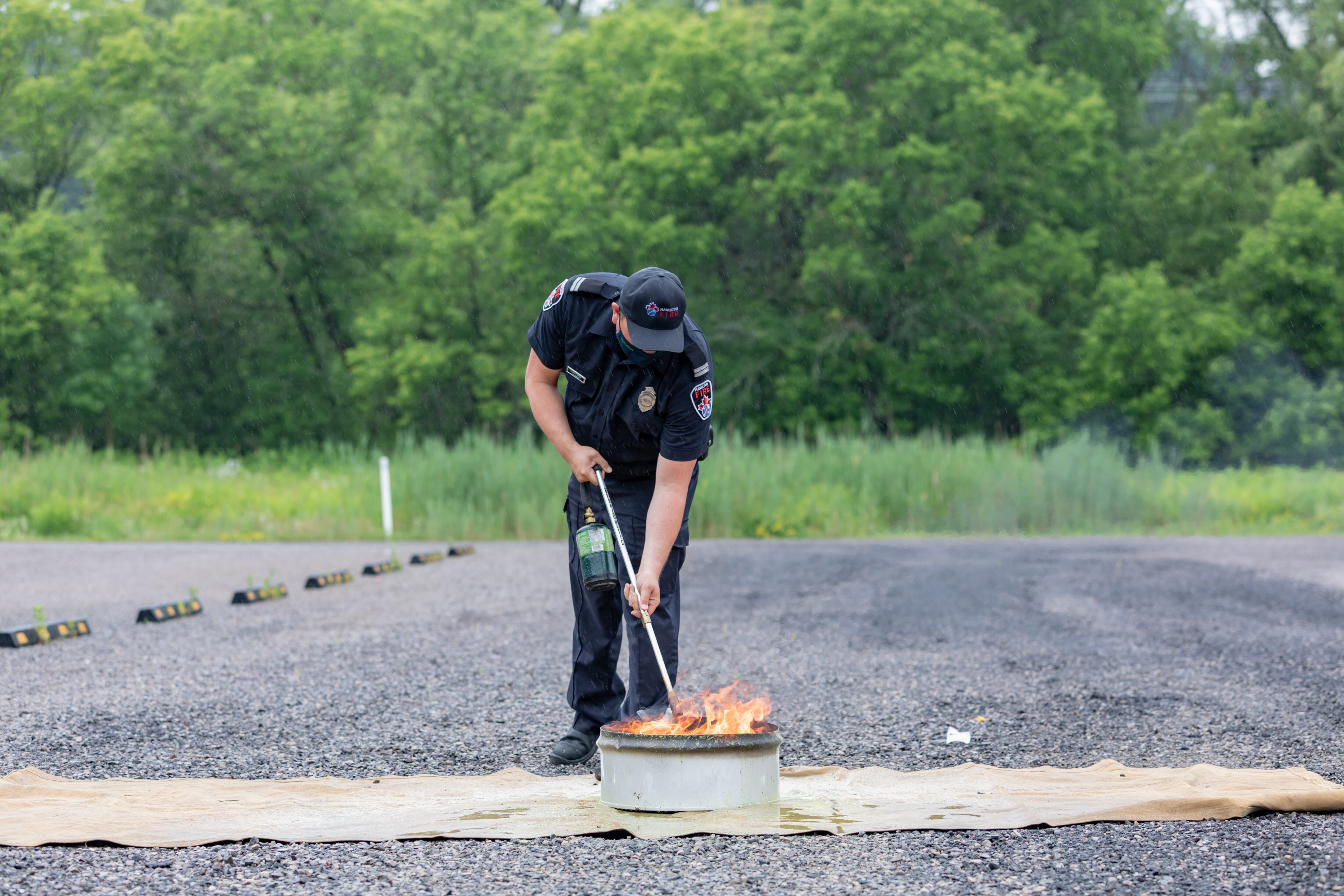A firefighter lights a fire in a container. 