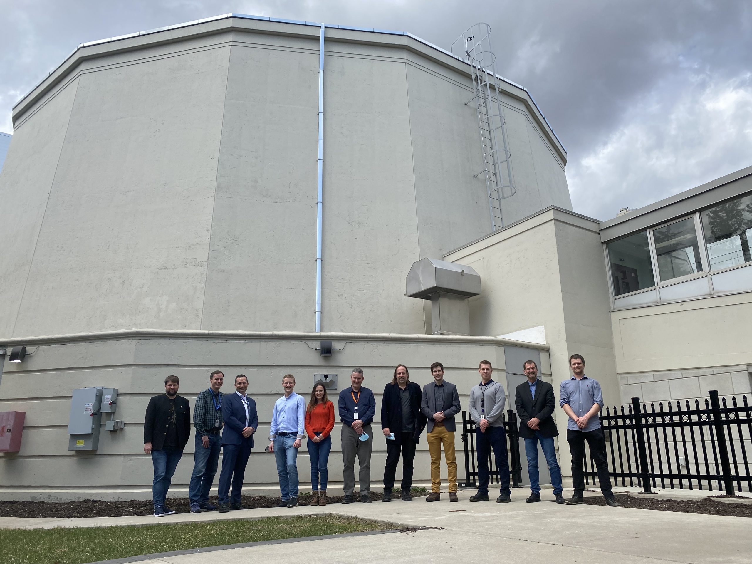 A group of people stand outside the McMaster Nuclear Reactor.