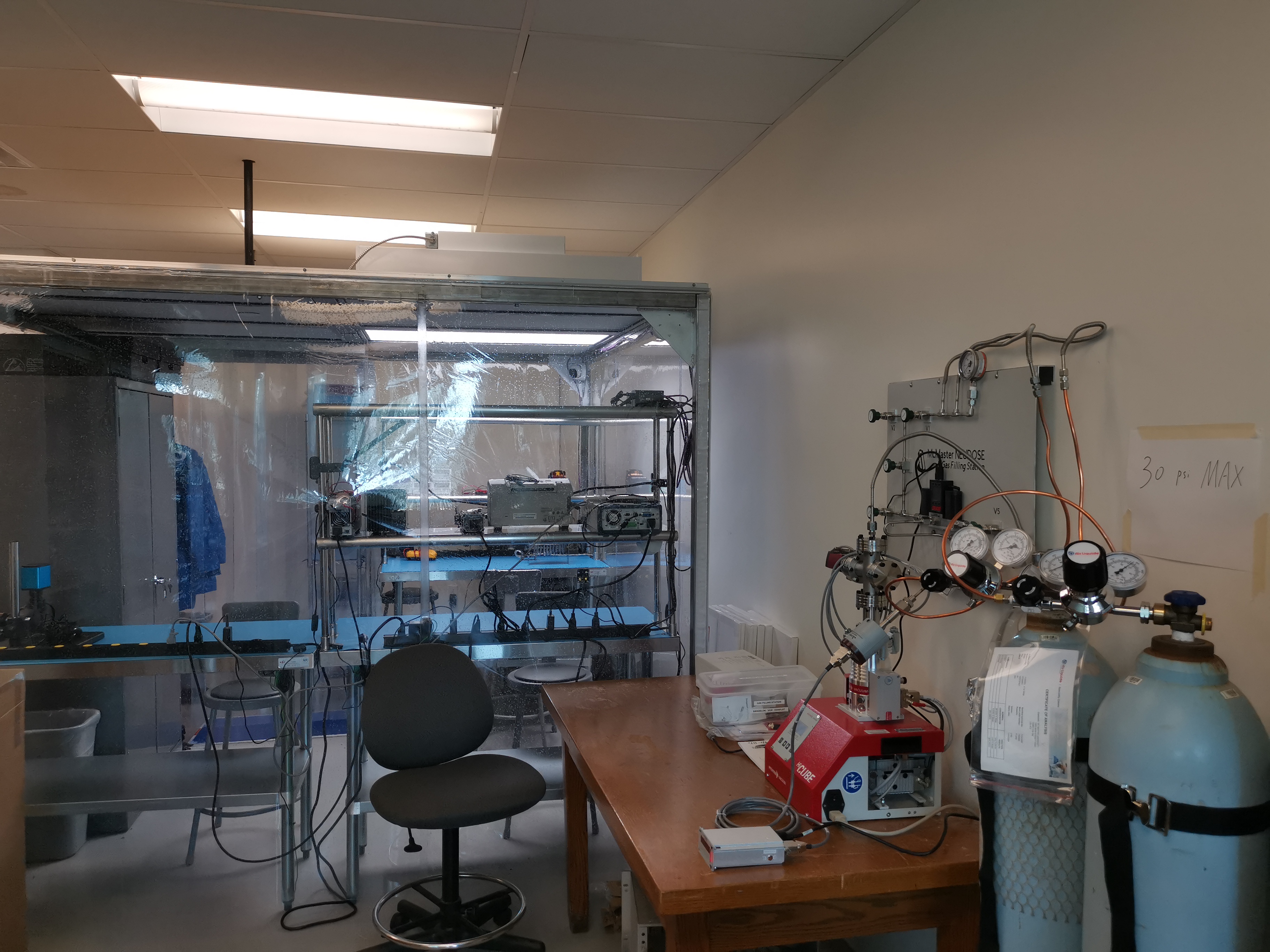 A lab with a table and chair in the foreground and a clean room in the background. 