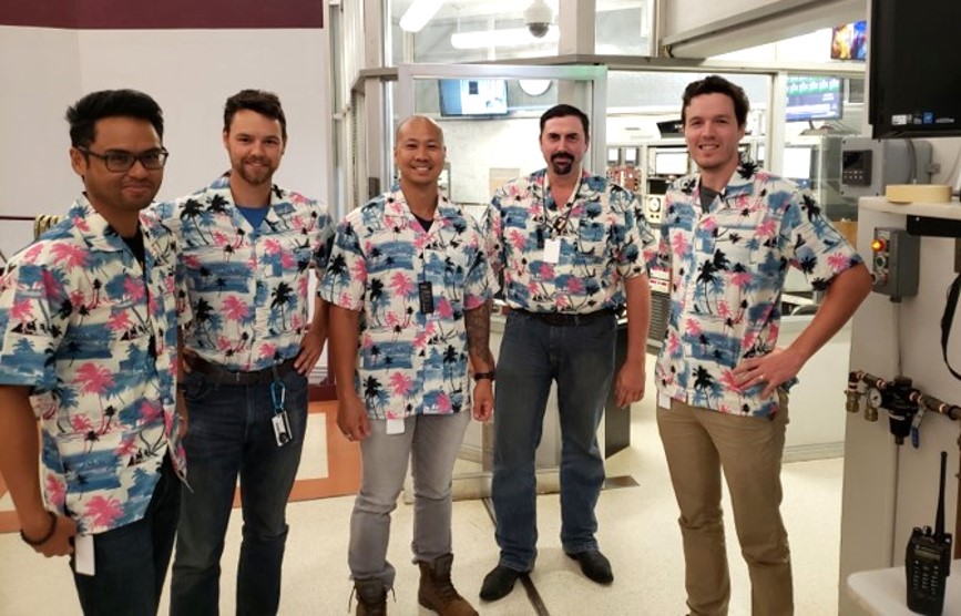 Group of five men wearing matching Hawaiian shirts.